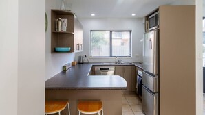 Una cocina moderna con una isla central, taburetes de bar, horno empotrado y refrigerador.
