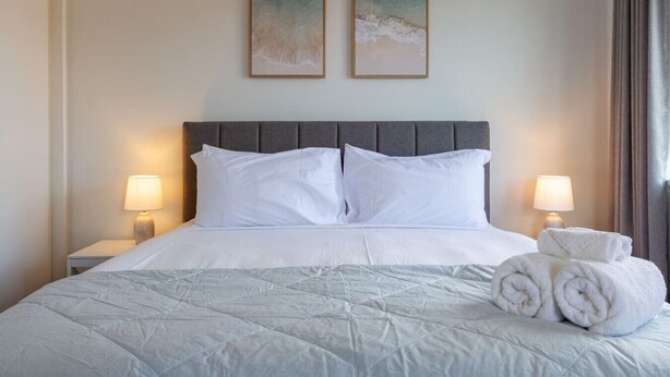 Una habitación de hotel con una cama grande, dos lámparas de noche y dos cuadros en la pared.