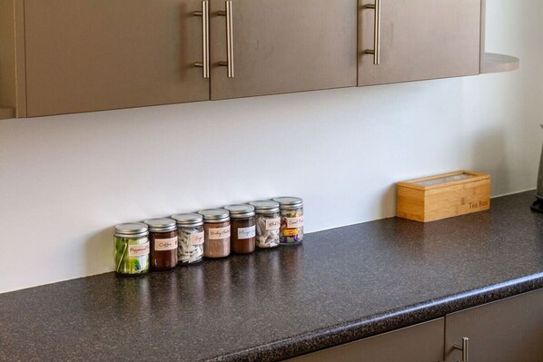 Una encimera de cocina con botes de especias y una caja de té.