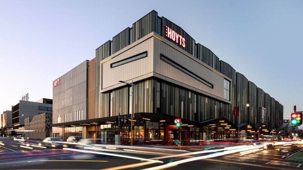 A modern hotel with a prominent 'HOYTS' sign, featuring a contemporary design with large windows and a flat roof.