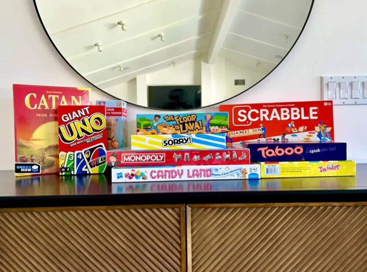 Une variété de jeux de société est disposée sur une table, et un miroir reflète la pièce.