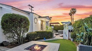 A modern house with a well-maintained lawn, a fire pit, and a patio area. - PB Hot Tub Triplex 5BR, MiniGolf, Games & Parking! (San Diego)