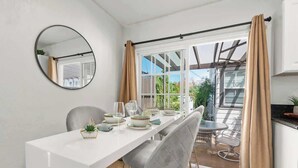 A dining area with a white table, grey chairs, and a round mirror on the wall. - PB Hot Tub Triplex 5BR, MiniGolf, Games & Parking! (San Diego)