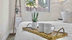 A neatly made bed with a woven tray holding a potted plant and two white cups. - Stunning 4BR Villa with Bay Views & Rooftop Decks! (San Diego)