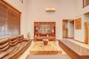 A modern living room with a brown leather sofa, a wooden coffee table, and a decorative wooden panel with shelves. - Collection O Near Mrt Cipete Raya (Jakarta)