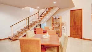 A modern interior with a wooden staircase, a dining area with chairs and a table, and a wooden door. - Collection O Near Mrt Cipete Raya (Jakarta)