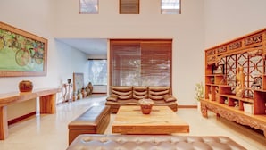 A spacious living room with a large sectional sofa, a wooden coffee table, and a decorative wooden shelf. - Collection O Near Mrt Cipete Raya (Jakarta)