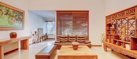 A spacious living room with a large sectional sofa, a wooden coffee table, and a decorative wooden shelf.