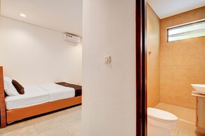Una habitación con una cama, un inodoro blanco y un baño con lavamanos.