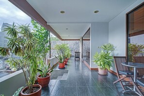 A balcony with potted plants, a table, and chairs. - Collection O Near Mrt Cipete Raya (Jakarta)