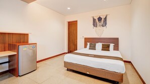 A hotel room with a bed, a wooden desk, and a refrigerator. - Collection O Near Mrt Cipete Raya (Jakarta)