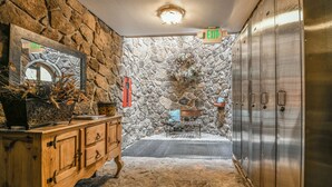 A stone-walled bathroom with a wooden vanity, a bench, and a metal locker. - Chateaux Dumont 2702 (Keystone)