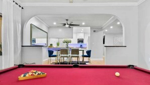 A pool table with a red felt surface, a cue ball, and a rack of billiard balls. - Massive 5BR Resort Style Retreat with Heated Pool (San Diego)