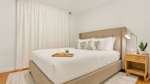 A bedroom with a bed, bedside table, lamp, and curtains. - Massive 5BR Resort Style Retreat with Heated Pool (San Diego)