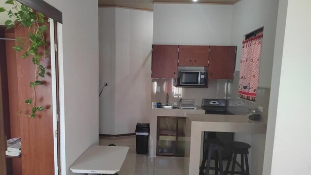 A compact kitchen with a microwave, a small island with stools, and a table. - Centrally located and furnished apartment for short stays (San José)