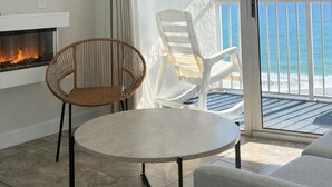 A balcony with a view of the ocean, a fireplace, a round table, and two chairs.