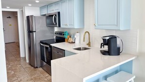 A modern kitchen with stainless steel appliances, light blue cabinets, and a white countertop.