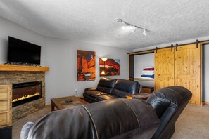 Ein modernes Wohnzimmer mit Kamin aus Stein, einer Ledersofa und einem Flachbildfernseher.