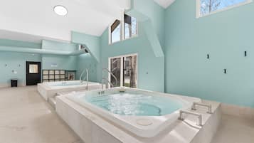 A spa area with two hot tubs, a staircase, and a view of the outdoors.