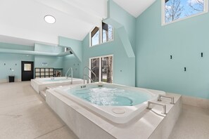Ein Wellnessbereich mit zwei Whirlpools, einer Treppe und Blick ins Freie.