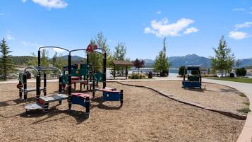 A playground with various play structures, a picnic area, and a view of mountains in the background.