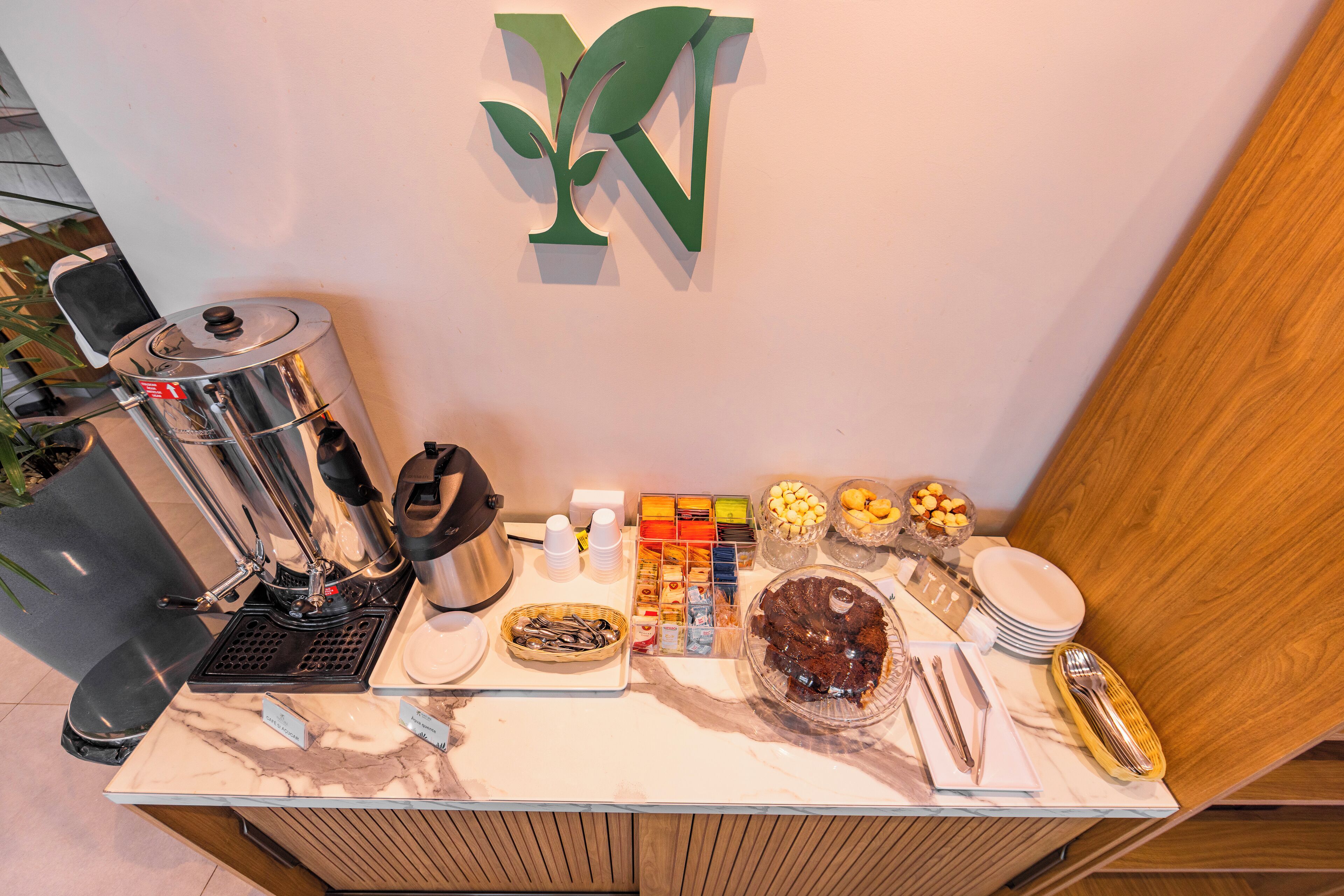 Una mesa de mármol con un bufé, una máquina de café, diferentes recipientes de comida y utensilios.