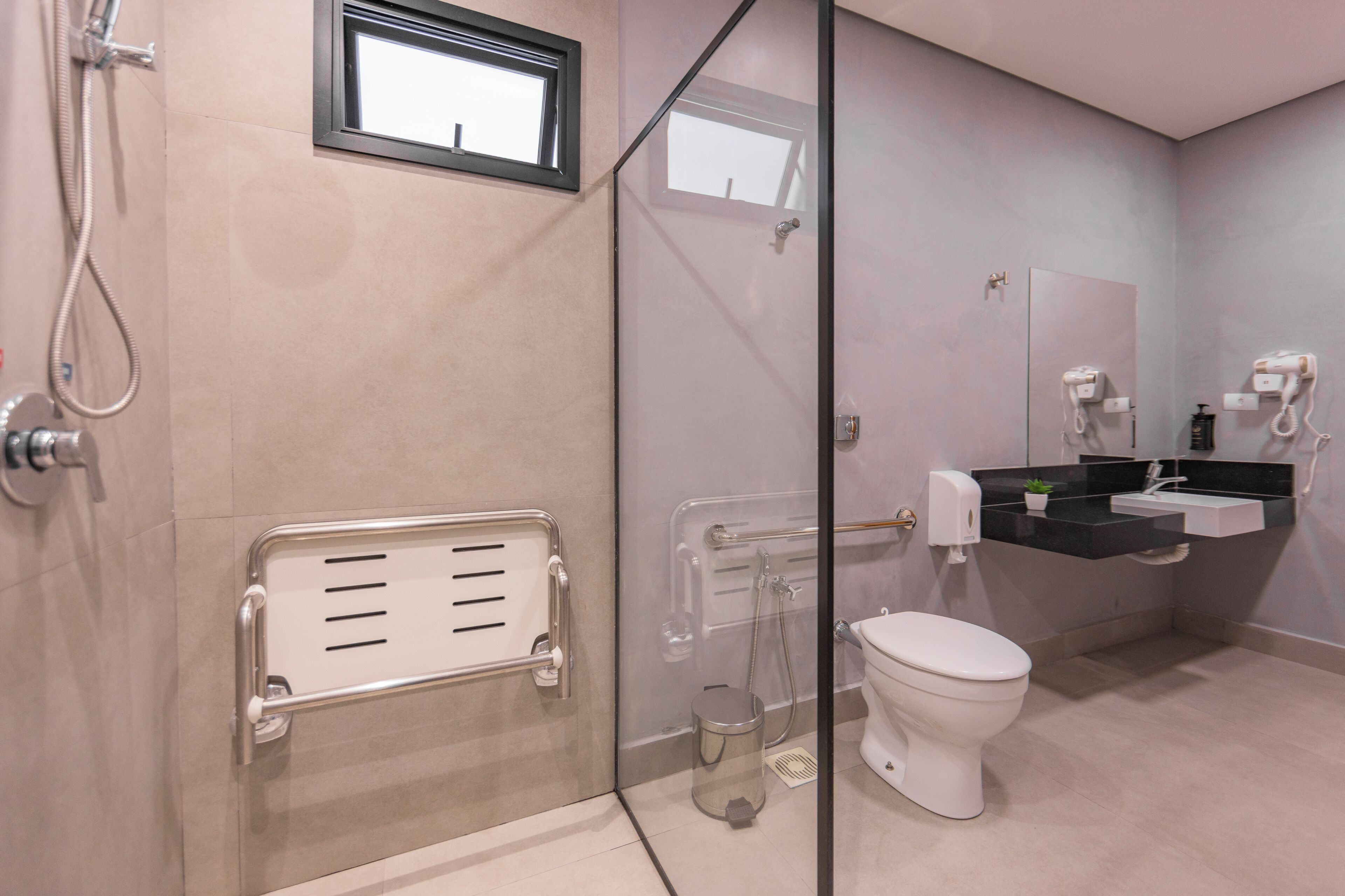 Un baño moderno con cabina de ducha de vidrio, inodoro y lavamanos con encimera negra.