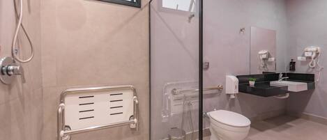 Un baño moderno con cabina de ducha de vidrio, inodoro y lavamanos con encimera negra.