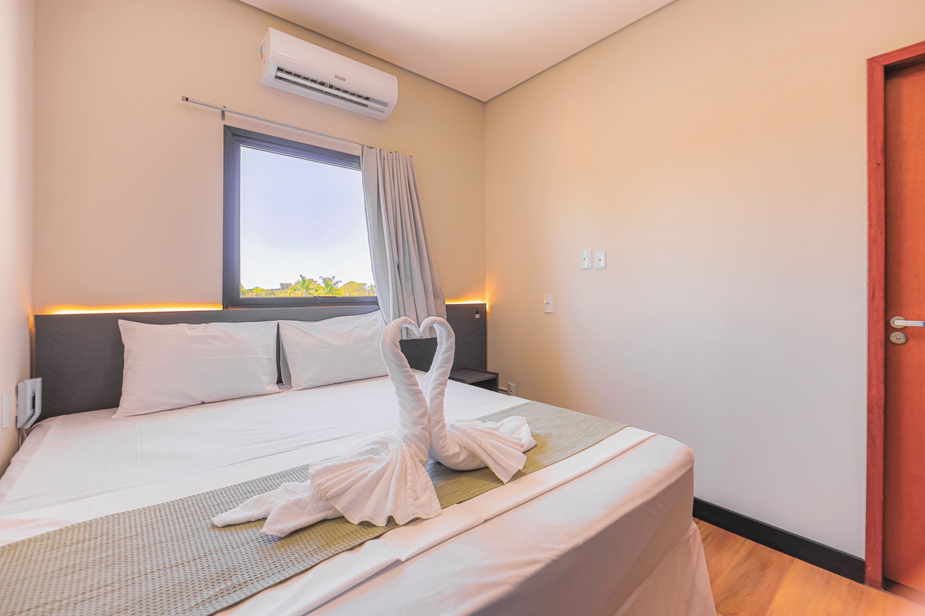 Een hotelkamer met een bed, een raam, een airconditioning en een deur.