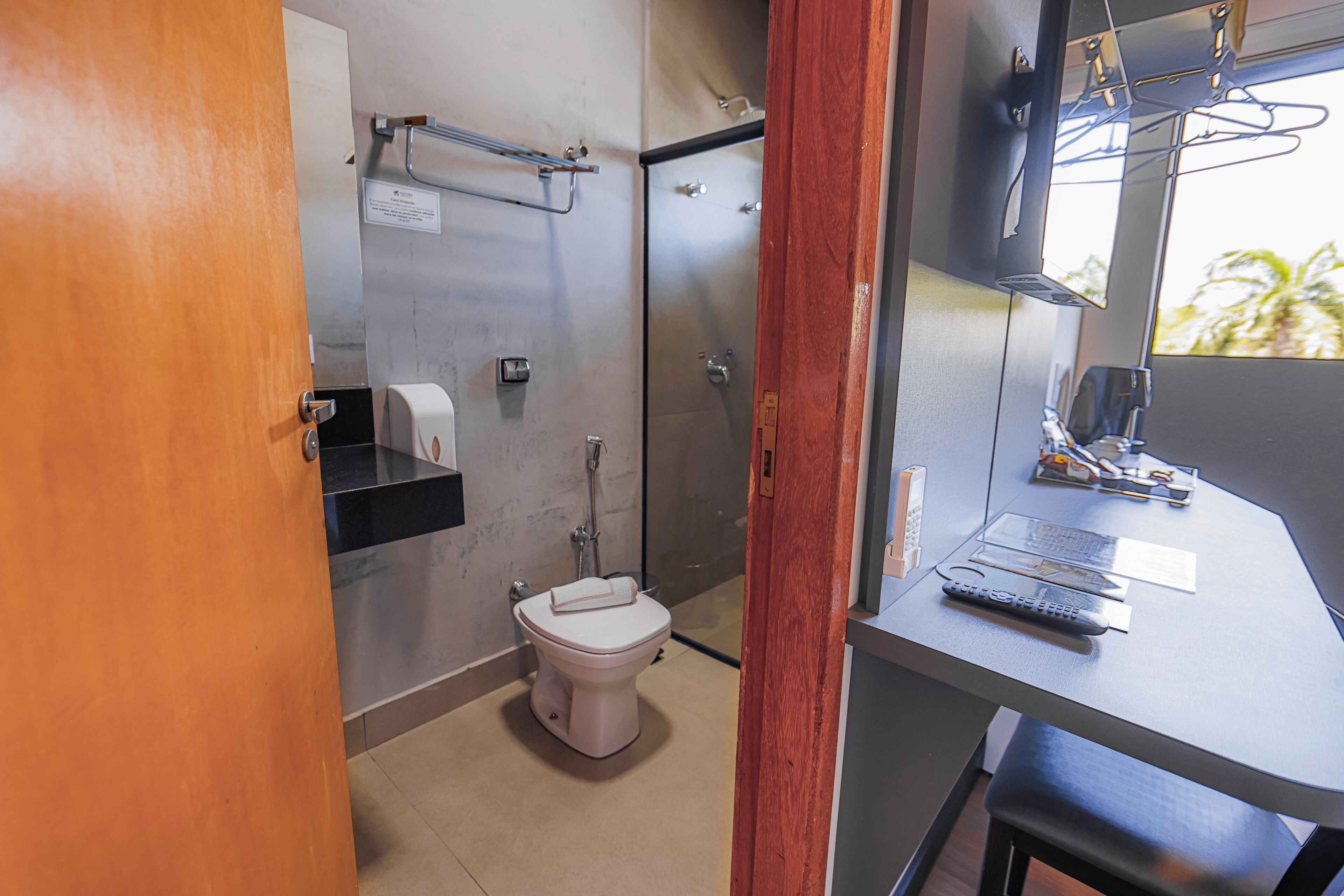 Bagno con toilette, doccia e un piccolo tavolo con telecomando.