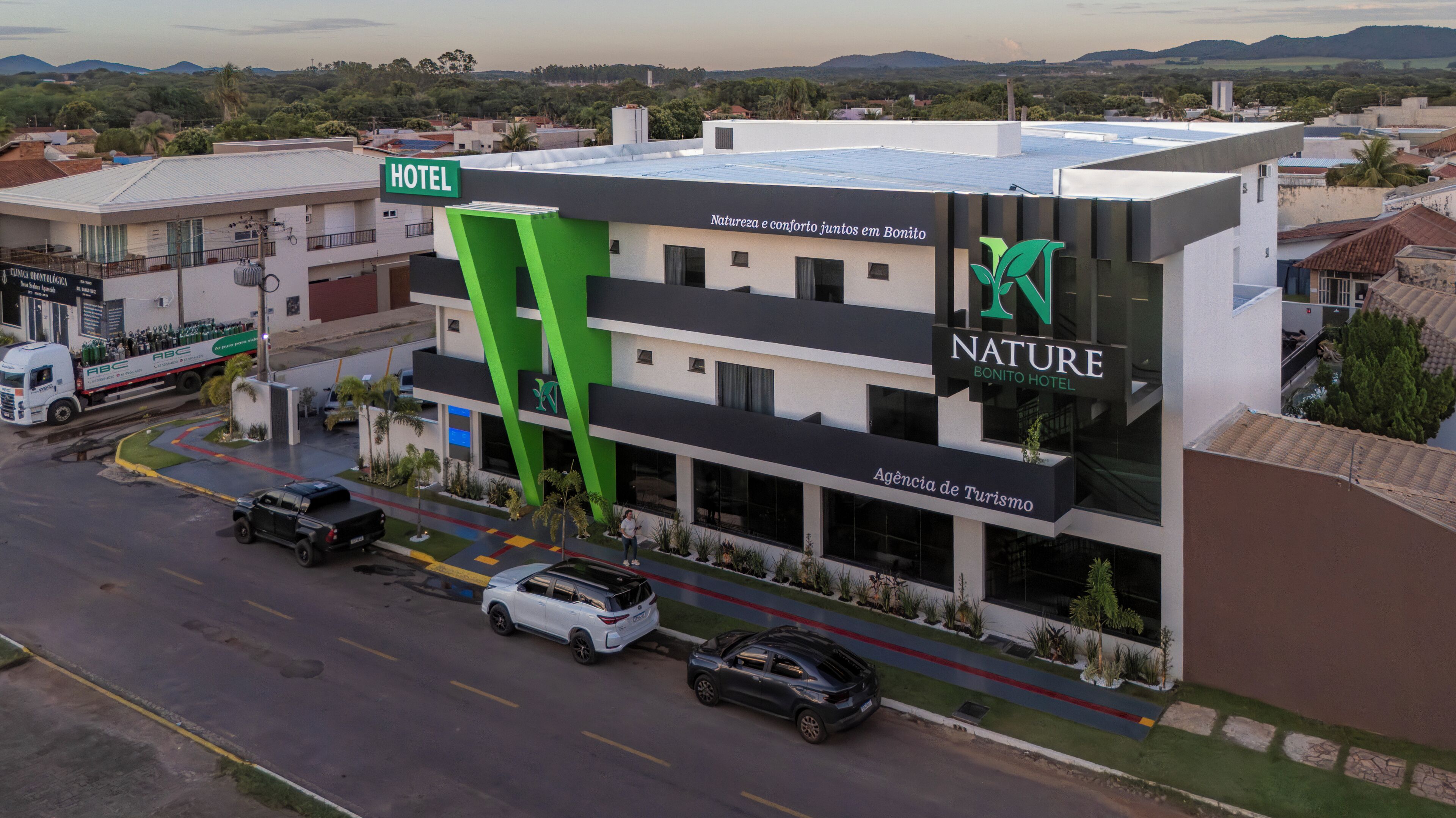 A hotel with a prominent green 'HOTEL' sign, a 'NATURE BONITO HOTEL' sign, and a 'Natureza e conforto juntos en Bonito' sign.