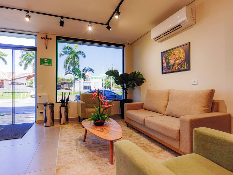 A reception area with a sofa, a coffee table, and a plant. There is a door leading outside, and a painting on the wall.