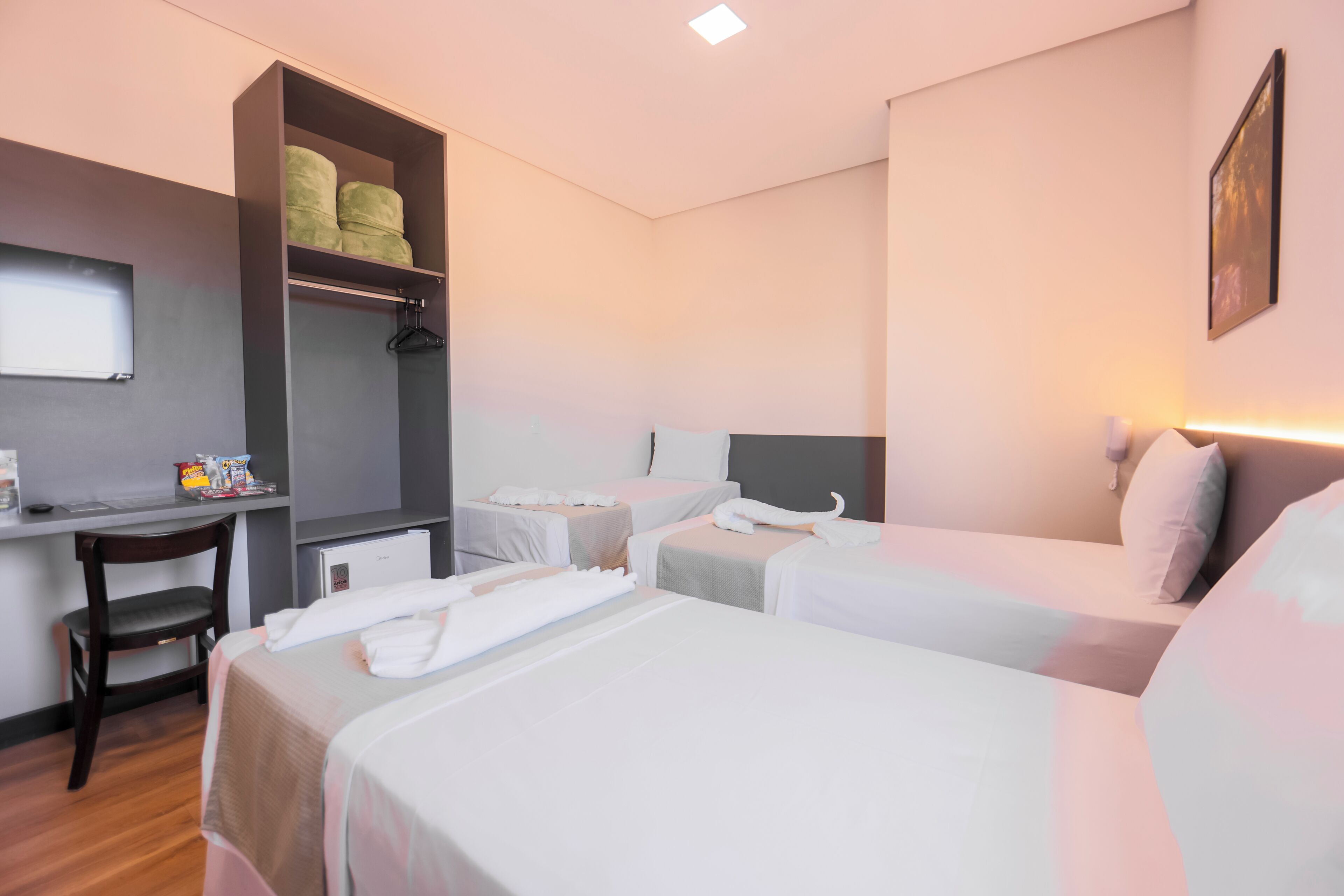 Habitación de hotel con dos camas, un escritorio, un armario y una mesita.