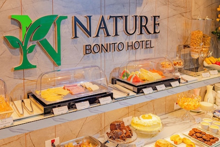 A buffet with various food items, a sign for 'Nature Bonito Hotel,' and a decorative plant.. Nature Bonito Hotel