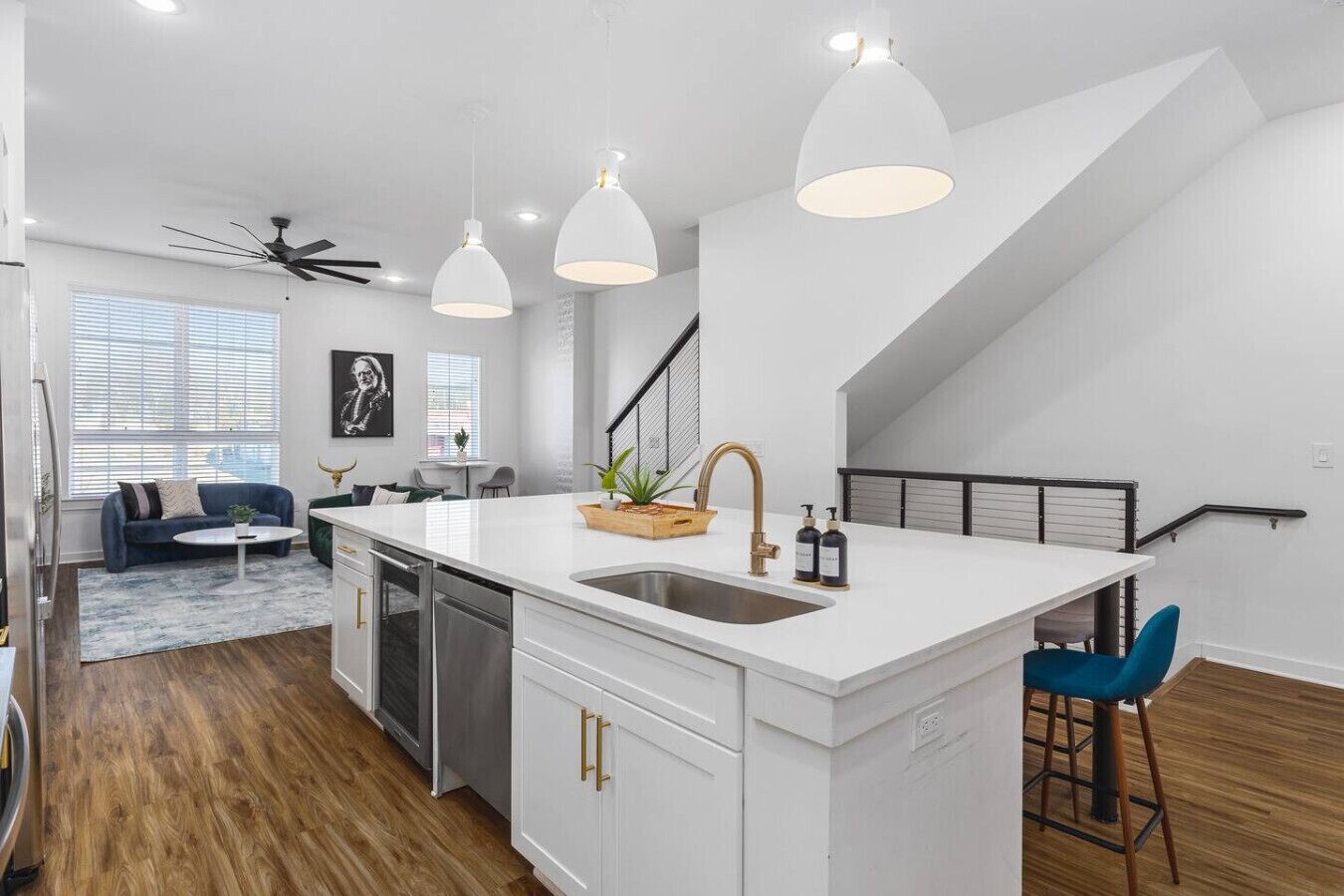 A modern kitchen with a central island, white cabinetry, and pendant lighting.