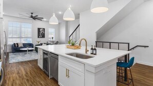 Una cocina moderna con una isla central, armarios blancos e iluminación colgante.