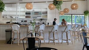 Een ruime bar met rieten stoelen en een toonbank.