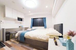 A compact hotel room with a bed, a desk with a chair, a TV, and a small window with curtains. - Near Ikebukuro, Tokyo 2-min Walk to Nishi-Sugamo Station Entire Place Up to 4 Guests (Tokyo)