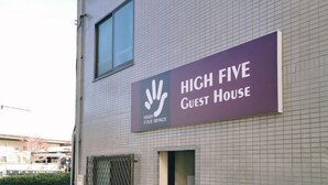 En byggnad med en skylt som visar texten ”HIGH FIVE Guest House”.