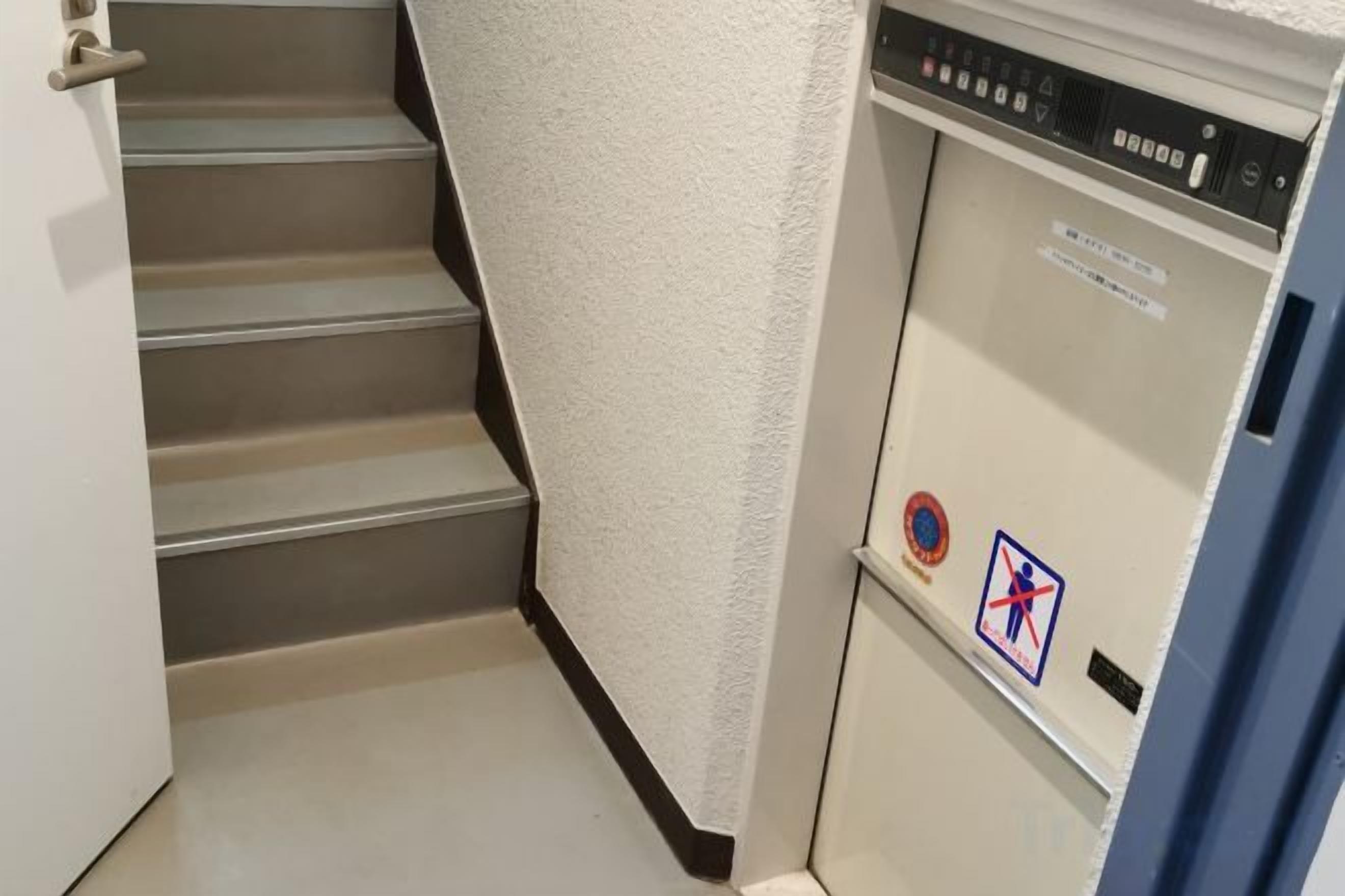 A staircase leading to a door with a control panel and a sign with a symbol.