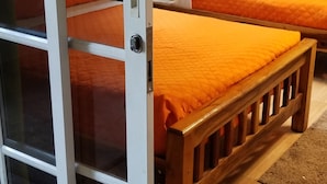 Een kamer met twee bedden, een schuifdeur en een kleine airconditioning op de muur.