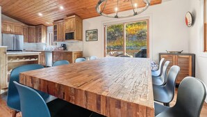 A spacious kitchen with wooden cabinets, a large dining table, and blue chairs. - Family-Friendly 5BR | Gather, Relax & Explore (Park City)