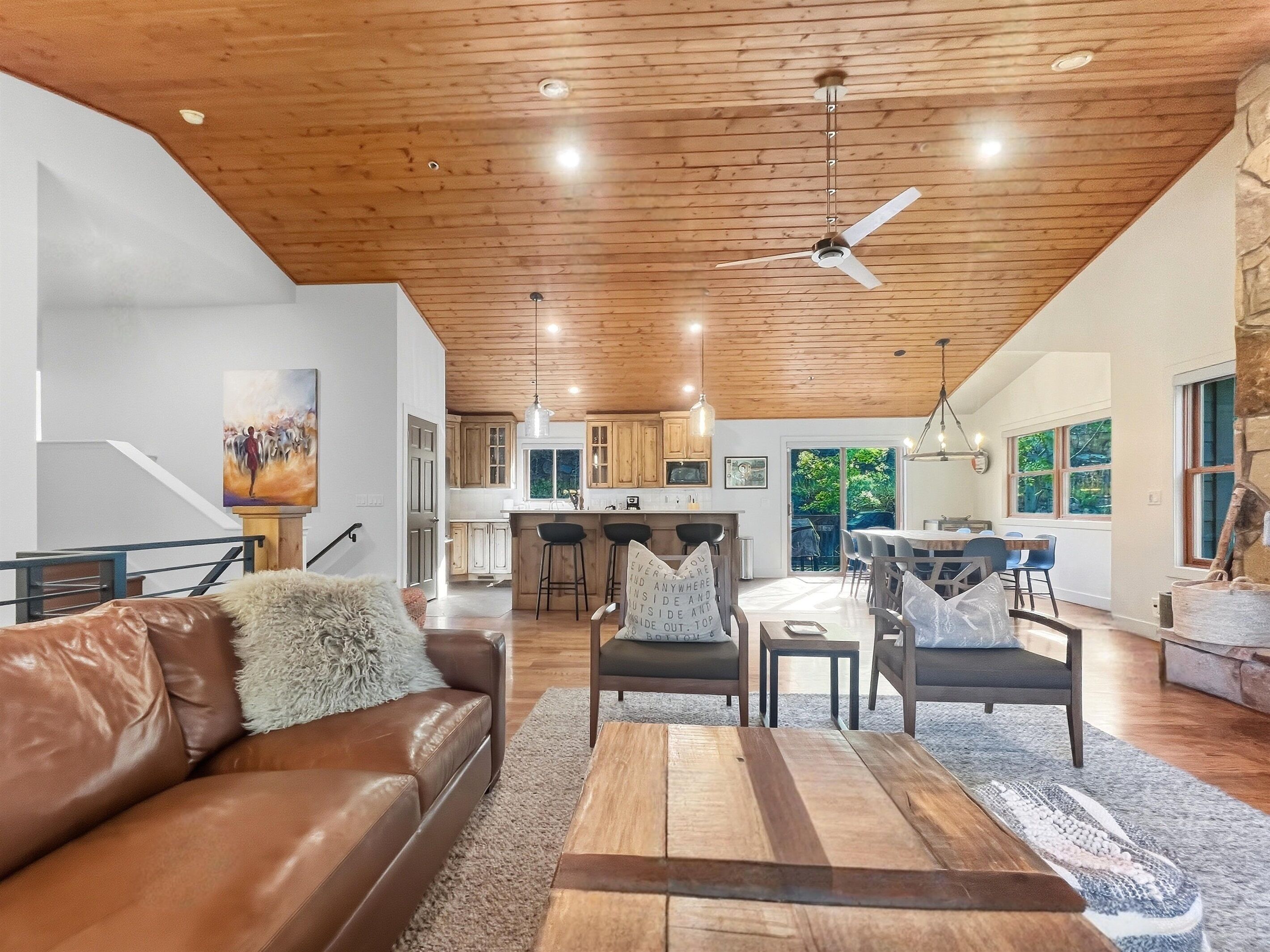 A spacious living area with a brown leather sofa, a wooden coffee table, and a dining area with a table and chairs.