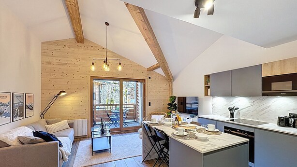 A modern kitchen with a large island, wooden beams, and a dining area with a view. - Tauari - Les Gets - Les Perrières (Les Gets)