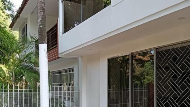 A modern two-story building with large windows, a wooden deck, and a metal fence. - Dilla House  (Cartagena)