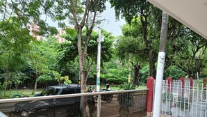A balcony with a view of a green park, a black car, and a white fence. - Dilla House  (Cartagena)