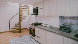 A kitchen with a spiral staircase, a microwave, and a built-in oven. - Dilla House  (Cartagena)