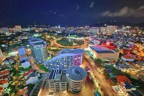 Une vue nocturne d’une ville, avec des bâtiments modernes, un rond-point et un stade.