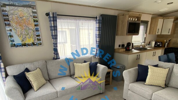 A living room with two sofas, a coffee table, a map on the wall, and a kitchen area. - Wanderer's Haven - Dog-Friendly Static Caravan near Cockermouth (Cockermouth)