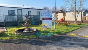 A holiday park sign with a fountain, a wooden bench, and a small building. - Wanderer's Haven - Dog-Friendly Static Caravan near Cockermouth (Cockermouth)